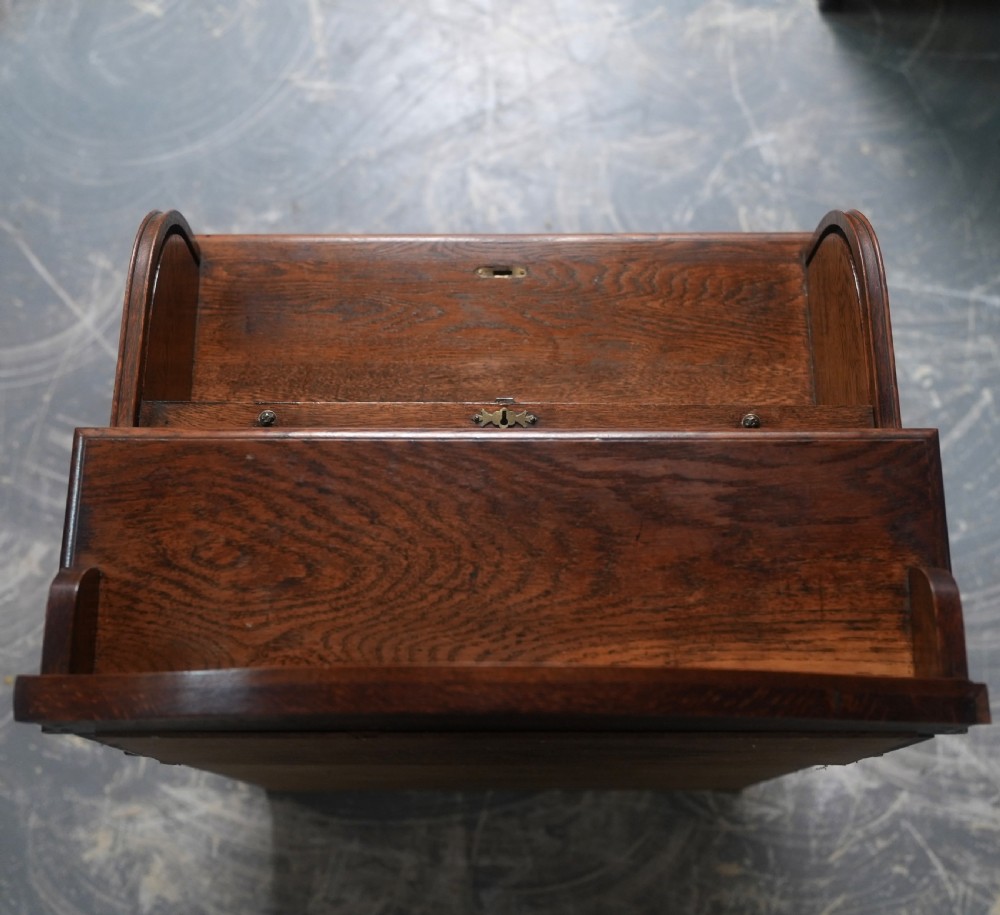 An Edwardian oak rolltop writing bureau featuring a tambour slatted shutter, a single frieze drawer with dark metal handles, an arched top gallery, and two open lower shelves. View IV