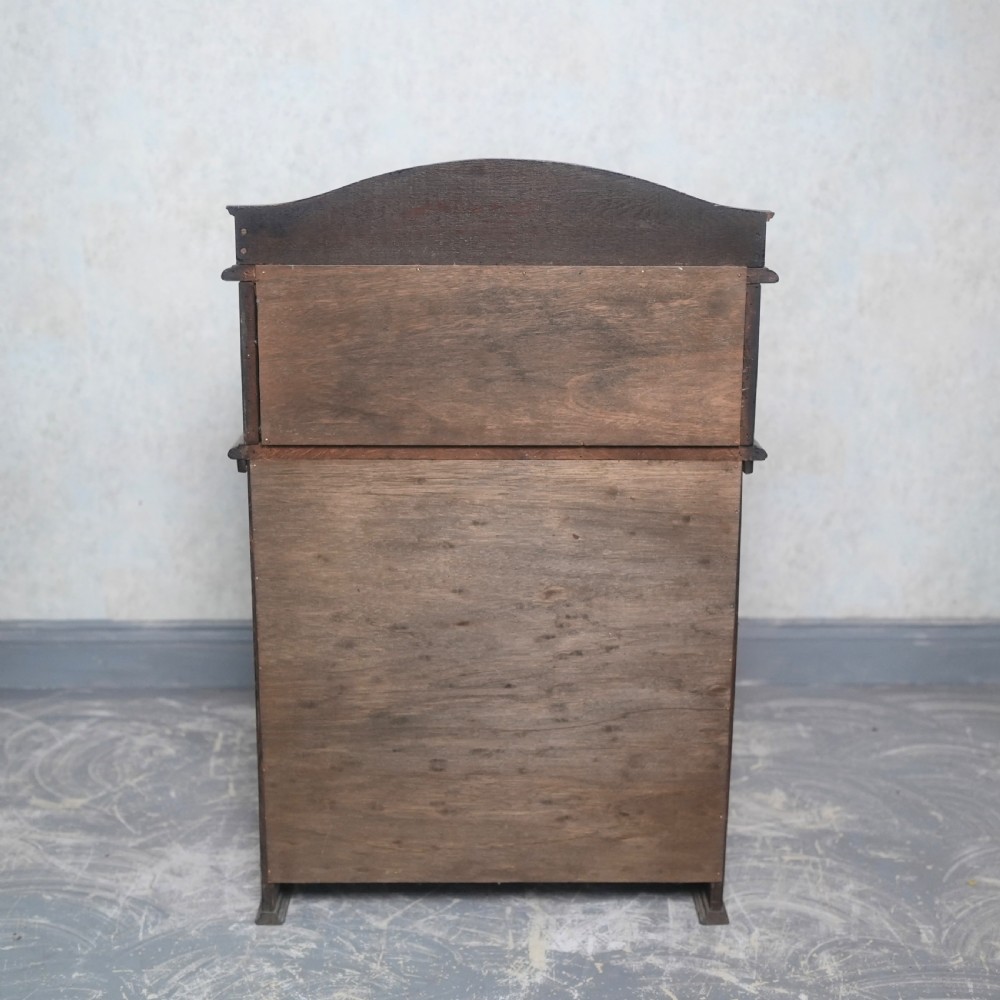 An Edwardian oak rolltop writing bureau featuring a tambour slatted shutter, a single frieze drawer with dark metal handles, an arched top gallery, and two open lower shelves. View X