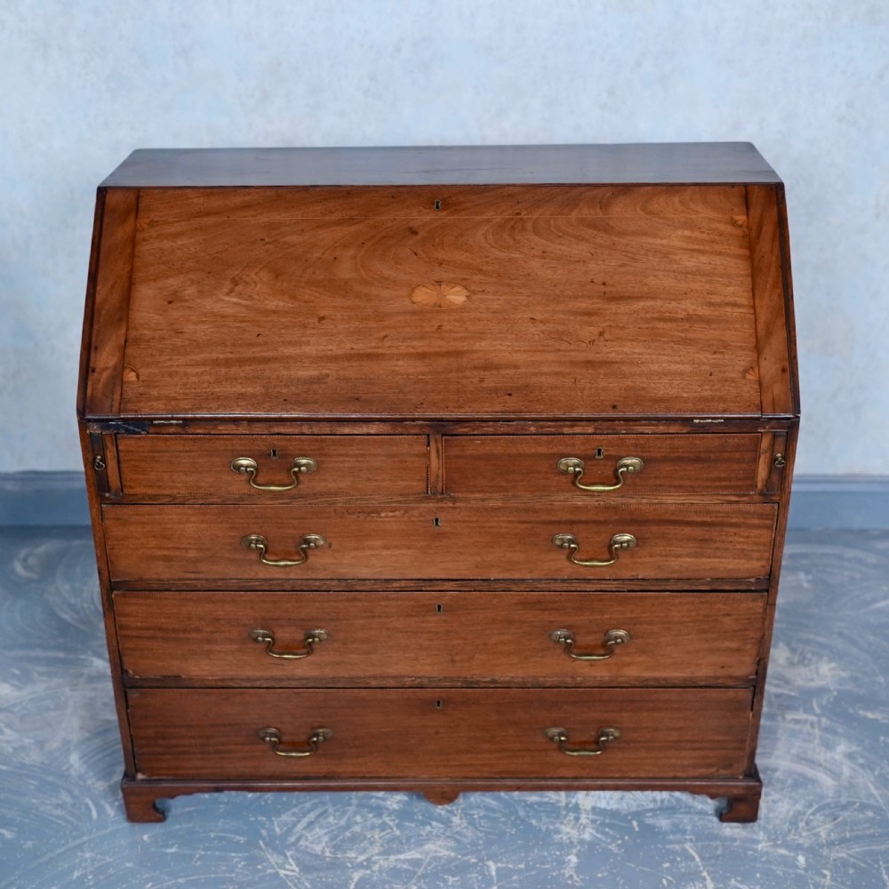 An antique Georgian mahogany writing bureau featuring a slanted fall-front top, four graduated drawers with brass swan-neck handles, and bracket feet. View III