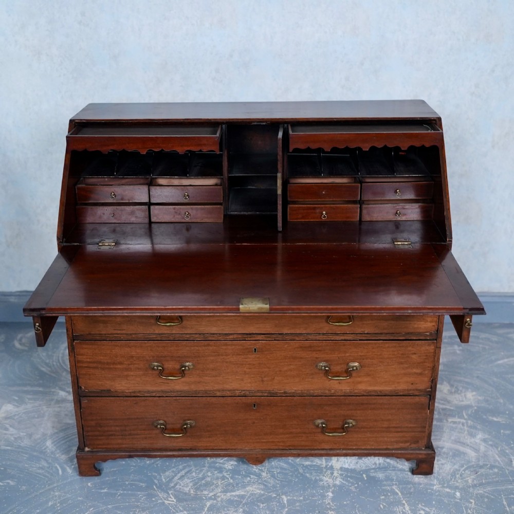 An antique Georgian mahogany writing bureau featuring a slanted fall-front top, four graduated drawers with brass swan-neck handles, and bracket feet. View VII