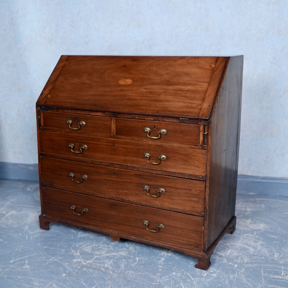 An antique Georgian mahogany writing bureau featuring a slanted fall-front top, four graduated drawers with brass swan-neck handles, and bracket feet. View VIII
