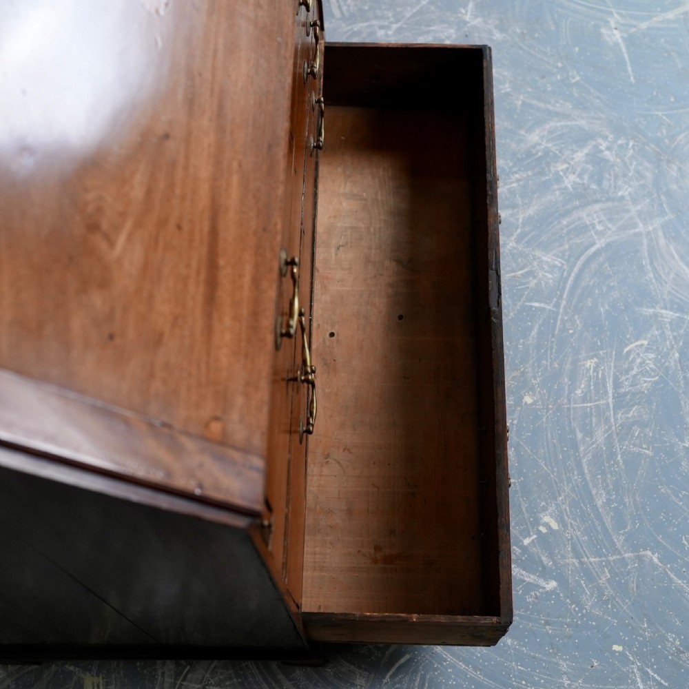 An antique Georgian mahogany writing bureau featuring a slanted fall-front top, four graduated drawers with brass swan-neck handles, and bracket feet. View XII