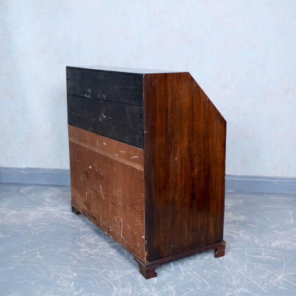 An antique Georgian mahogany writing bureau featuring a slanted fall-front top, four graduated drawers with brass swan-neck handles, and bracket feet. View XIII
