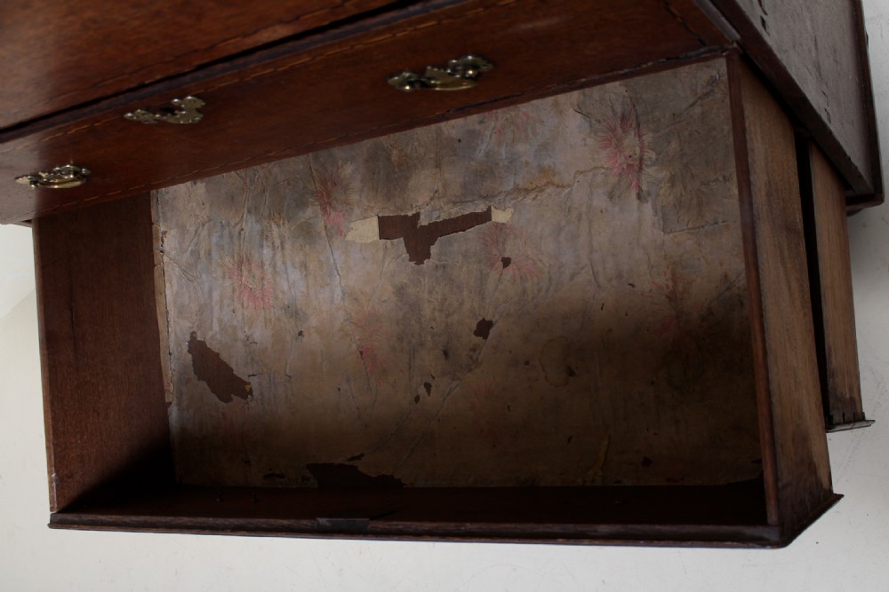 A tall 18th-century Georgian dark oak cupboard featuring panelled upper doors above six drawers with brass drop handles and stringing inlay, resting on turned feet. View XV
