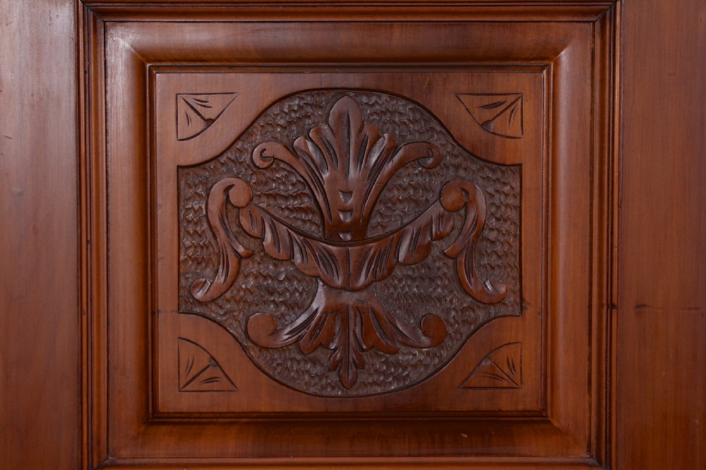 A Victorian triple-door mahogany wardrobe featuring a central mirrored door, carved foliate upper panels, and a solid plinth base. View X