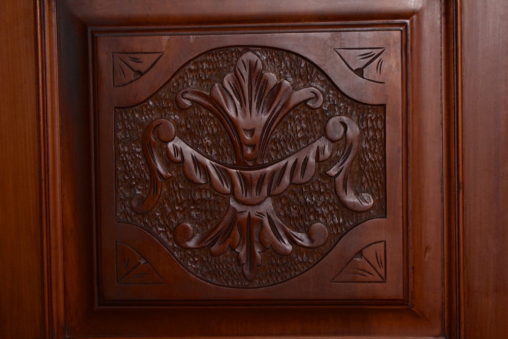 A Victorian triple-door mahogany wardrobe featuring a central mirrored door, carved foliate upper panels, and a solid plinth base. View XII