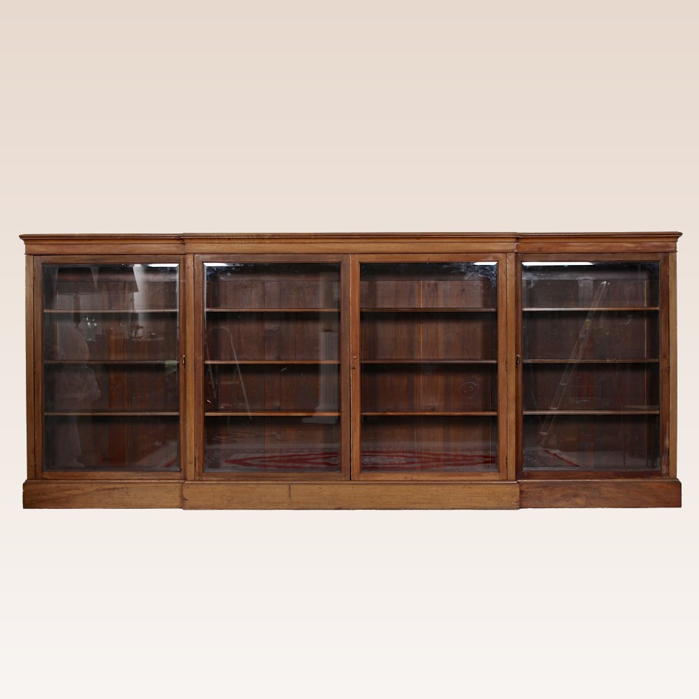 A low, wide Georgian mahogany breakfront bookcase featuring four glass doors and internal timber shelves.