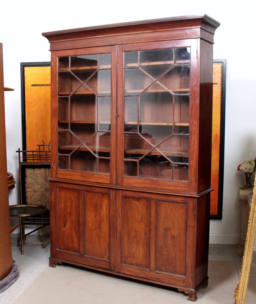 A tall Georgian mahogany glazed bookcase with geometric astragal glass doors set above a double panelled cupboard base resting on bracket feet.