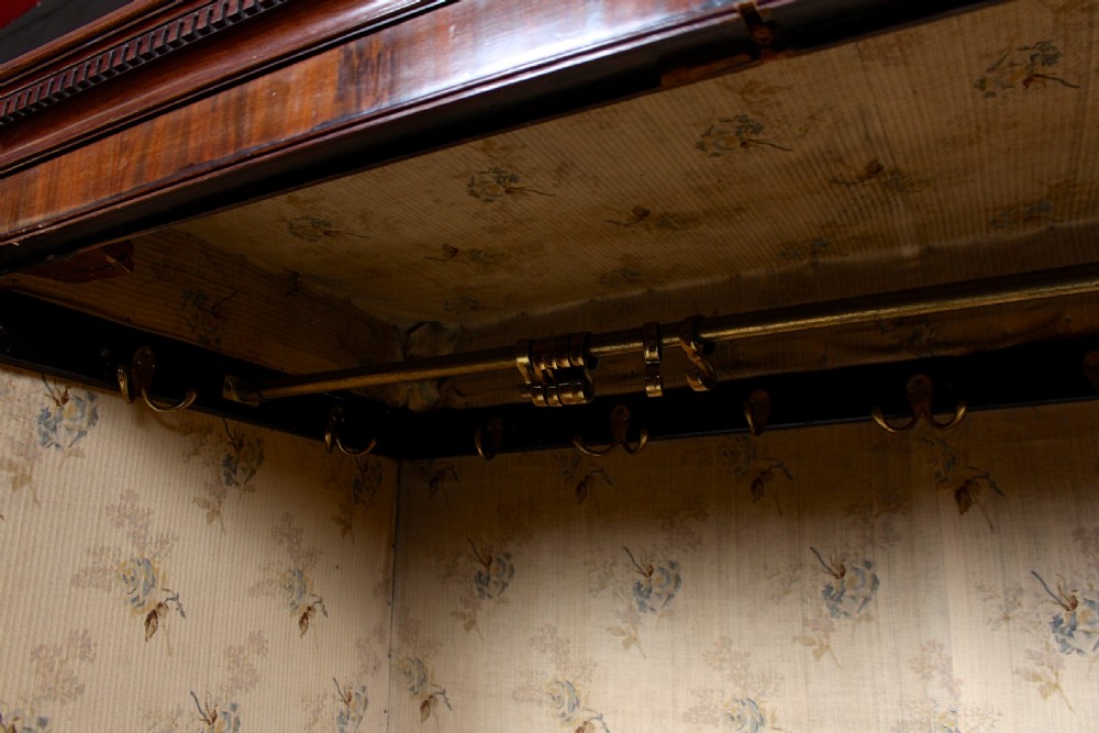 A tall 19th-century mahogany wardrobe featuring flame veneer double panel doors above lower drawers resting on bracket feet. View V