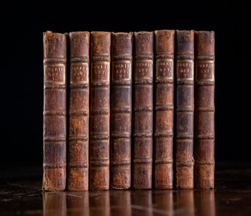 fig 1. An eight-volume set of 18th-century leather-bound books standing upright with visible raised spine bands and gilt titles.