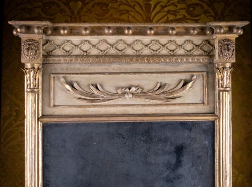 fig 1. A large Regency style painted and gilded pier mirror featuring classical fluted columns, lion mask corner accents, a ball-ornament cornice, and distressed mirror glass.