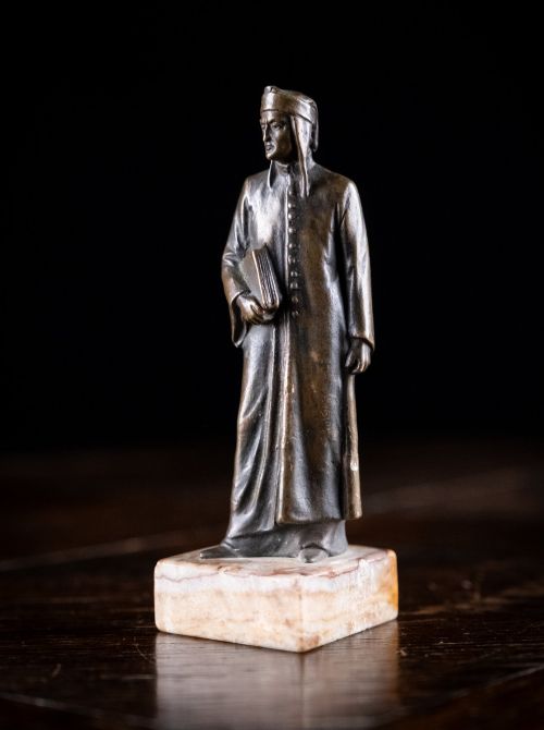 fig 1. A nineteenth-century dark bronze statuette depicting the poet Dante Alighieri standing in long robes and holding a book, mounted on a square veined marble base.