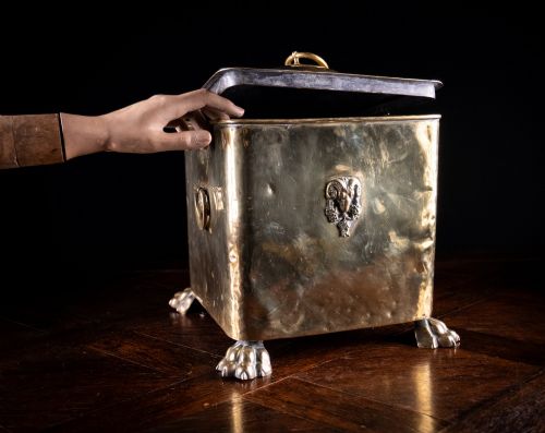 fig 1. A square Victorian brass coal bin featuring a domed lid with a top ring handle, cast ram head mounts, drop ring handles, and four claw and paw feet.