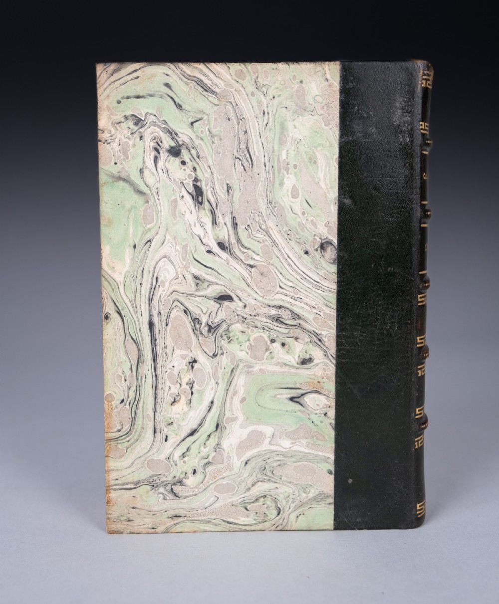 A half-leather bound book titled Life In Mexico with a dark brown spine featuring gilt geometric patterns and marbled paper boards. View V