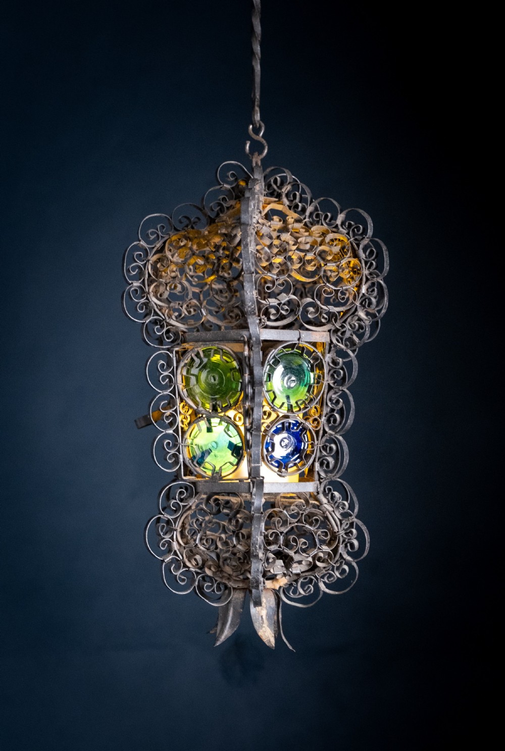 A 19th-century Venetian hanging lantern crafted from intricate wrought iron scrollwork with inset round coloured glass panels in green, blue, and amber. View II