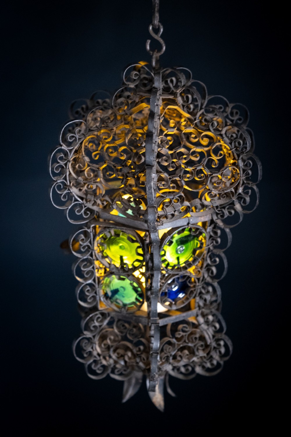A 19th-century Venetian hanging lantern crafted from intricate wrought iron scrollwork with inset round coloured glass panels in green, blue, and amber. View III