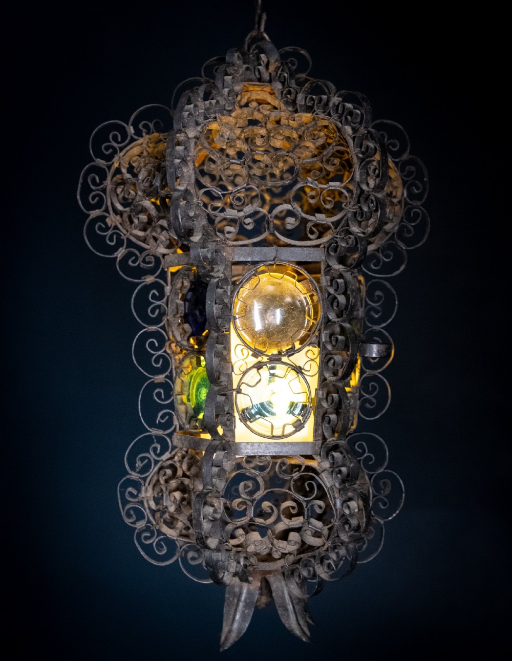 A 19th-century Venetian hanging lantern crafted from intricate wrought iron scrollwork with inset round coloured glass panels in green, blue, and amber. View VI