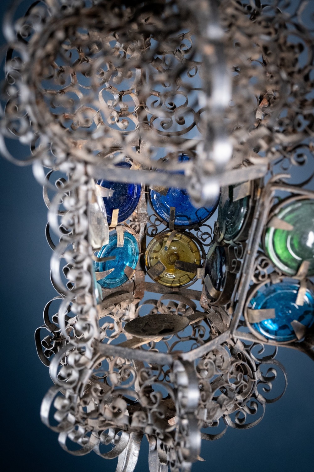 A 19th-century Venetian hanging lantern crafted from intricate wrought iron scrollwork with inset round coloured glass panels in green, blue, and amber. View VIII