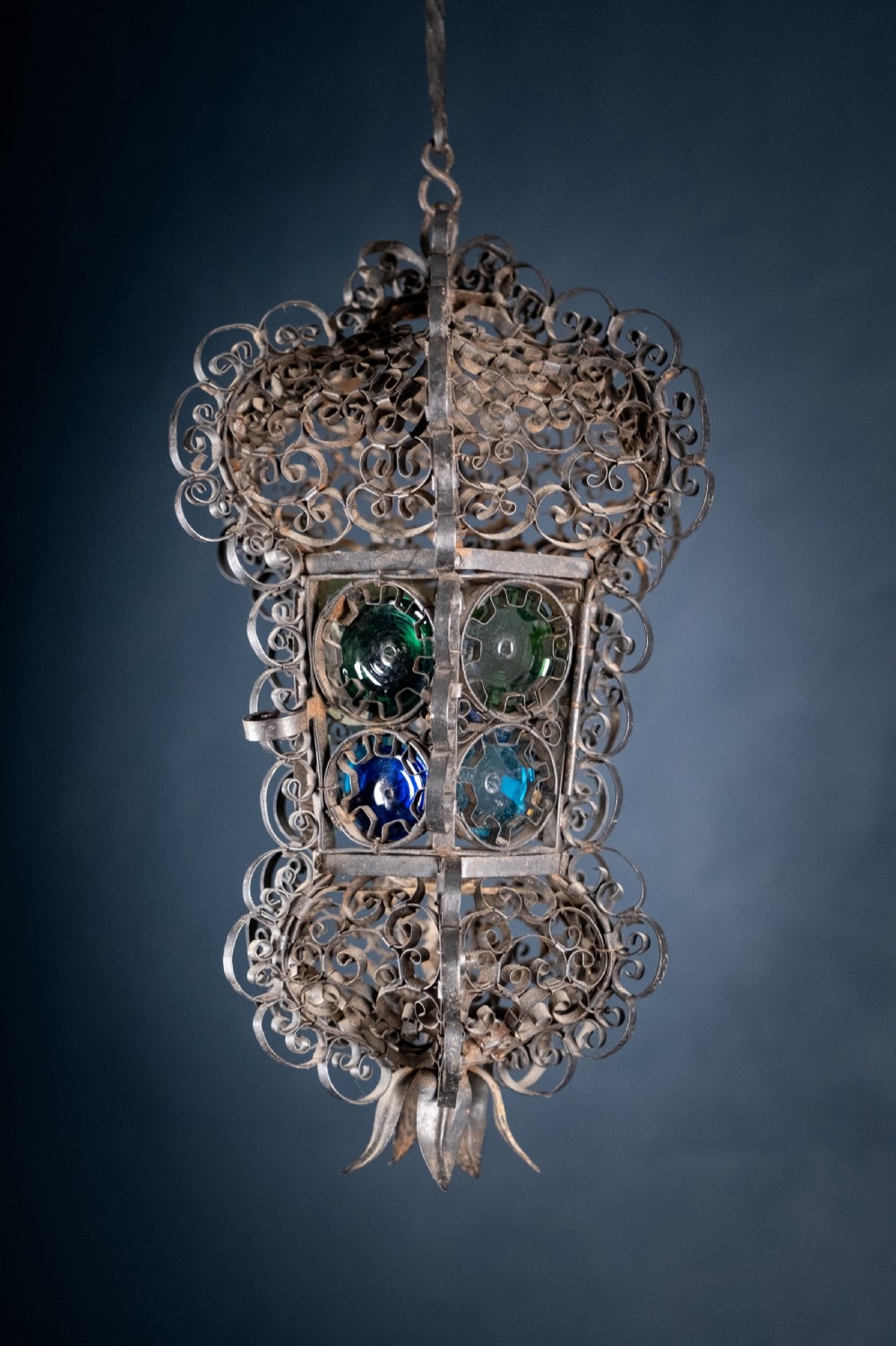 A 19th-century Venetian hanging lantern crafted from intricate wrought iron scrollwork with inset round coloured glass panels in green, blue, and amber. View X