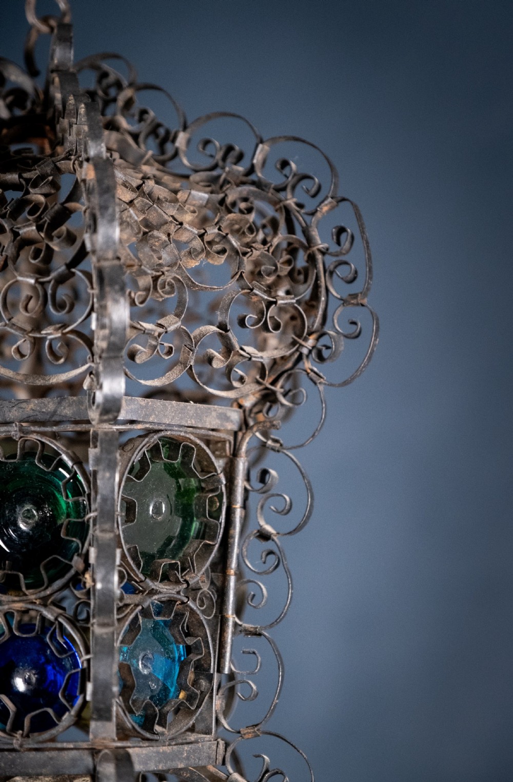 A 19th-century Venetian hanging lantern crafted from intricate wrought iron scrollwork with inset round coloured glass panels in green, blue, and amber. View XI