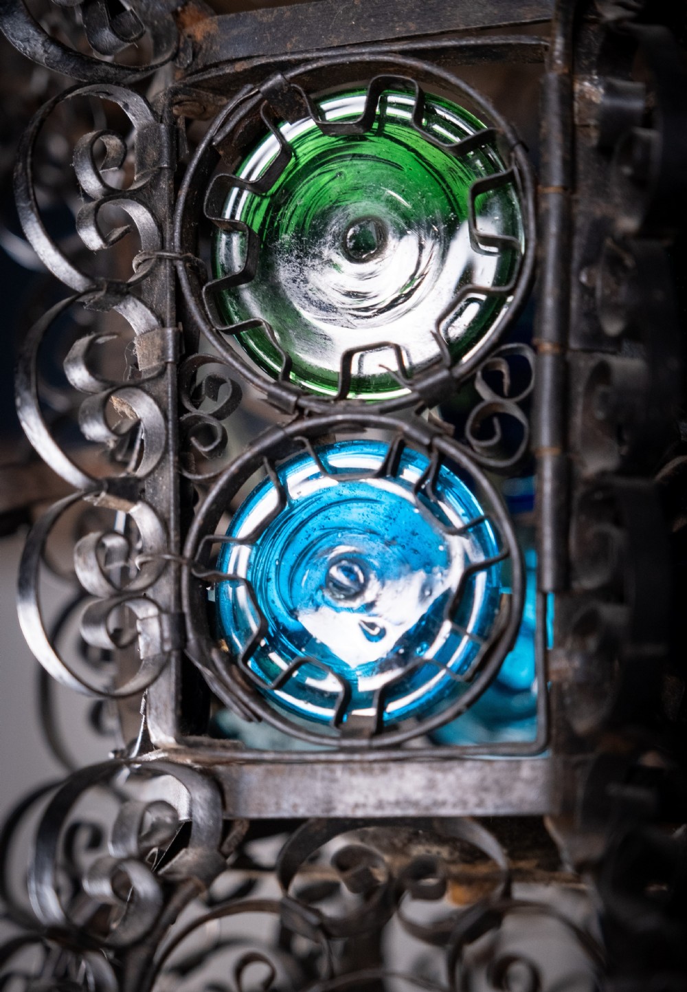 A 19th-century Venetian hanging lantern crafted from intricate wrought iron scrollwork with inset round coloured glass panels in green, blue, and amber. View XII