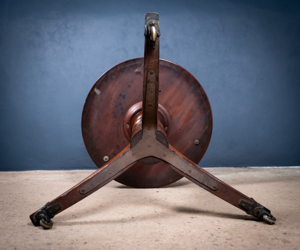 A two-tier Regency mahogany dumb waiter featuring a turned central column, brass uprights, and a tripartite base with castors. View XVII