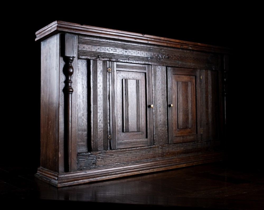A rectangular eighteenth-century oak wall cupboard featuring double panelled doors, geometric mouldings, and turned corner columns. View V