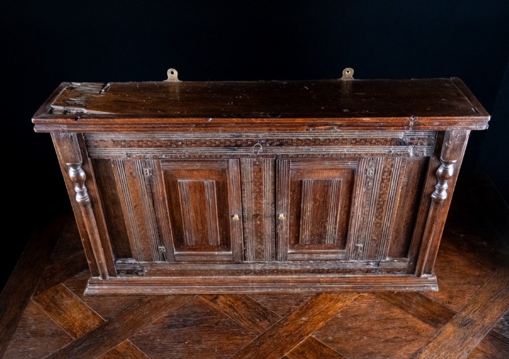 A rectangular eighteenth-century oak wall cupboard featuring double panelled doors, geometric mouldings, and turned corner columns. View VII