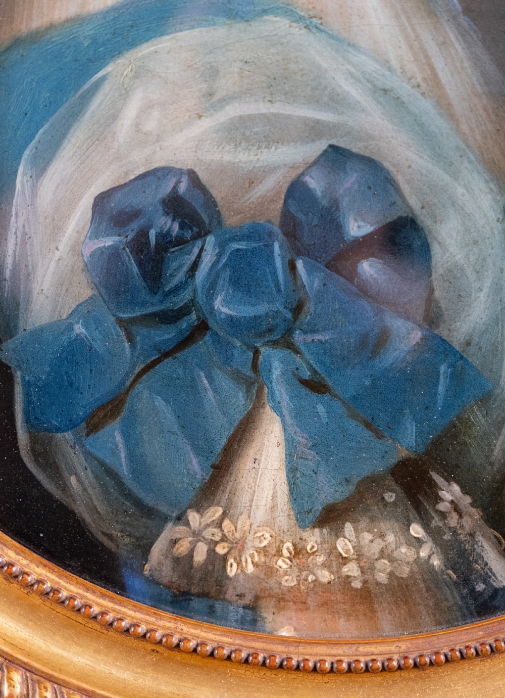 An oval 19th-century oil painting depicting the profile of a young girl wearing a blue dress and hair ribbon, enclosed in an ornate gold frame. View IV