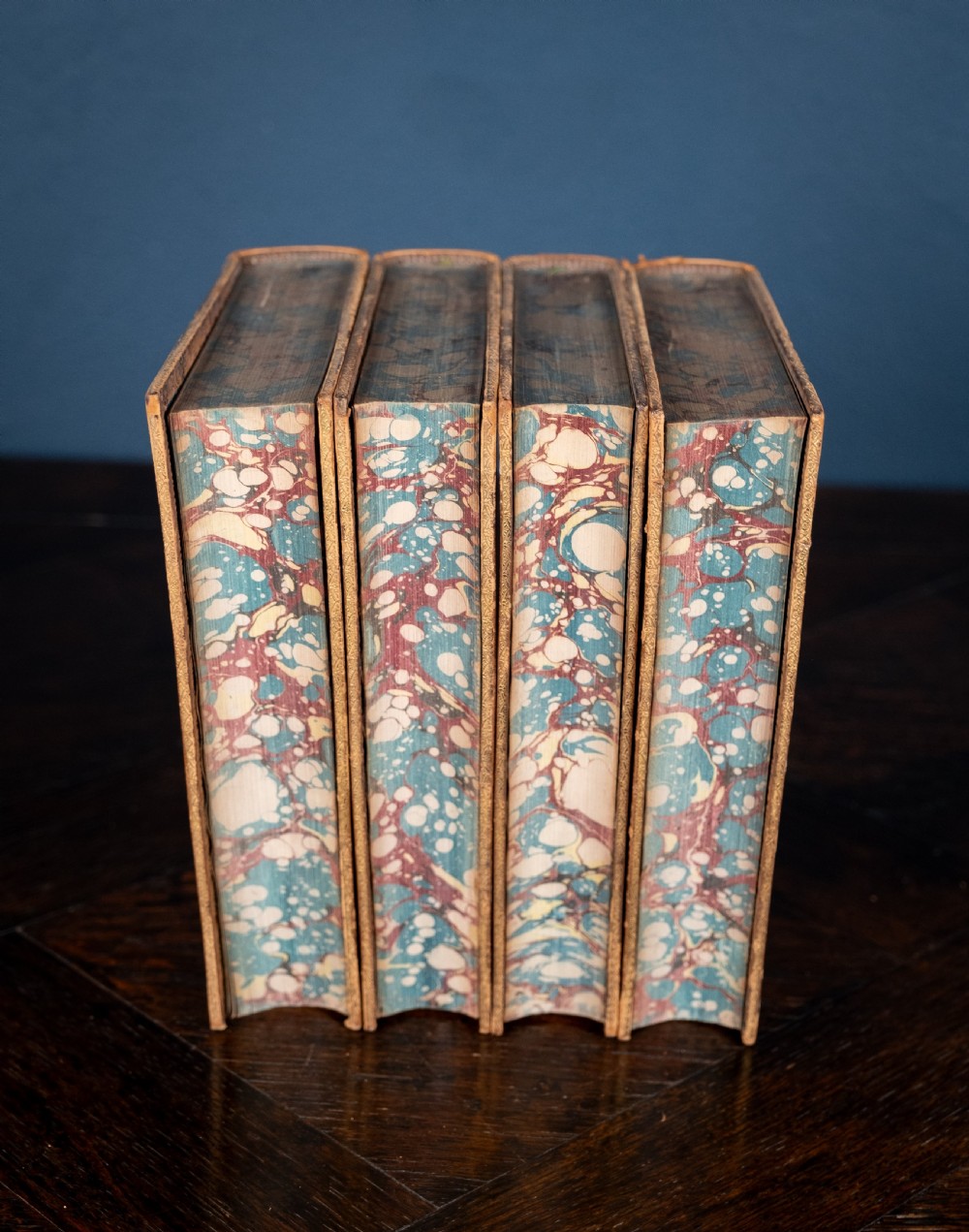 A four-volume set of 1881 Shakespeare leather-bound books standing upright, featuring heavily gilt-tooled spines with red and black title labels. View V