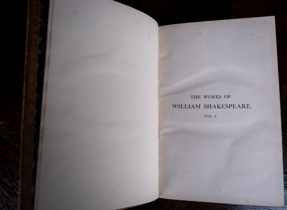A four-volume set of 1881 Shakespeare leather-bound books standing upright, featuring heavily gilt-tooled spines with red and black title labels. View XIII