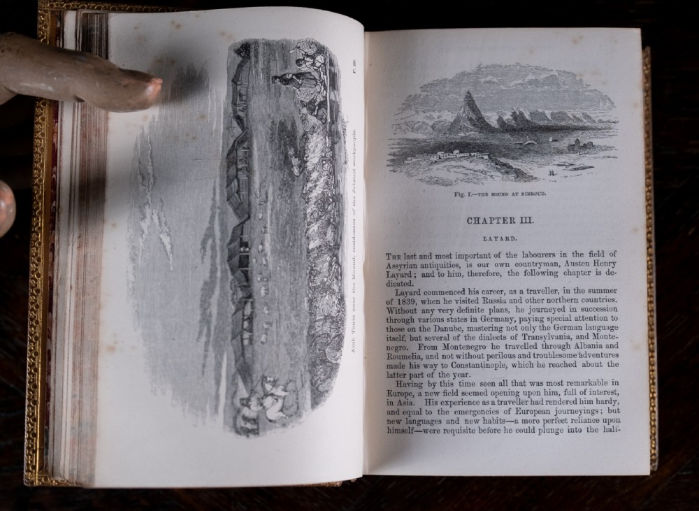 An 1857 tan leather-bound book titled Nineveh and Its Palaces featuring a gilded spine with raised bands and blind-tooled decoration. View VI