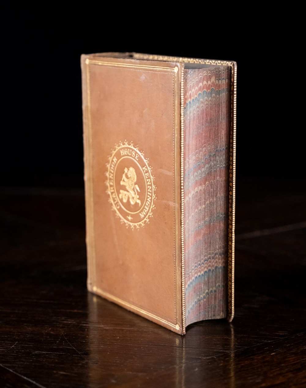 An 1857 tan leather-bound book titled Nineveh and Its Palaces featuring a gilded spine with raised bands and blind-tooled decoration. View VIII
