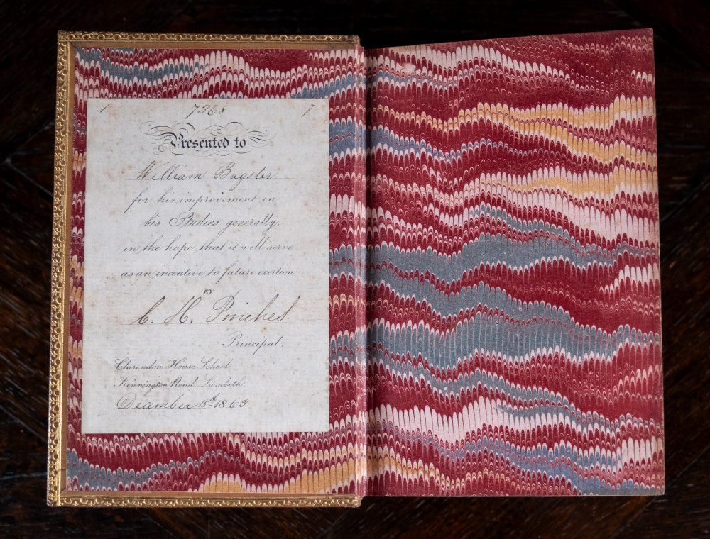 An 1857 tan leather-bound book titled Nineveh and Its Palaces featuring a gilded spine with raised bands and blind-tooled decoration. View IX