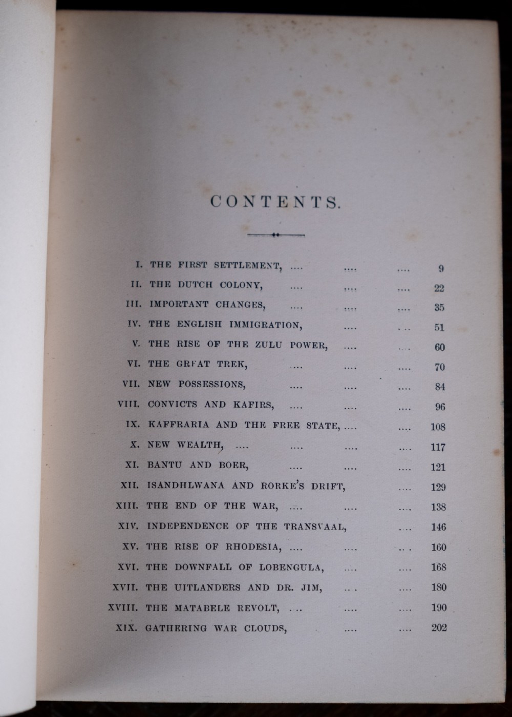 An Edwardian leather-bound book standing vertically, featuring a tan leather cover with detailed gold-tooled decorations and raised spine bands. View XII