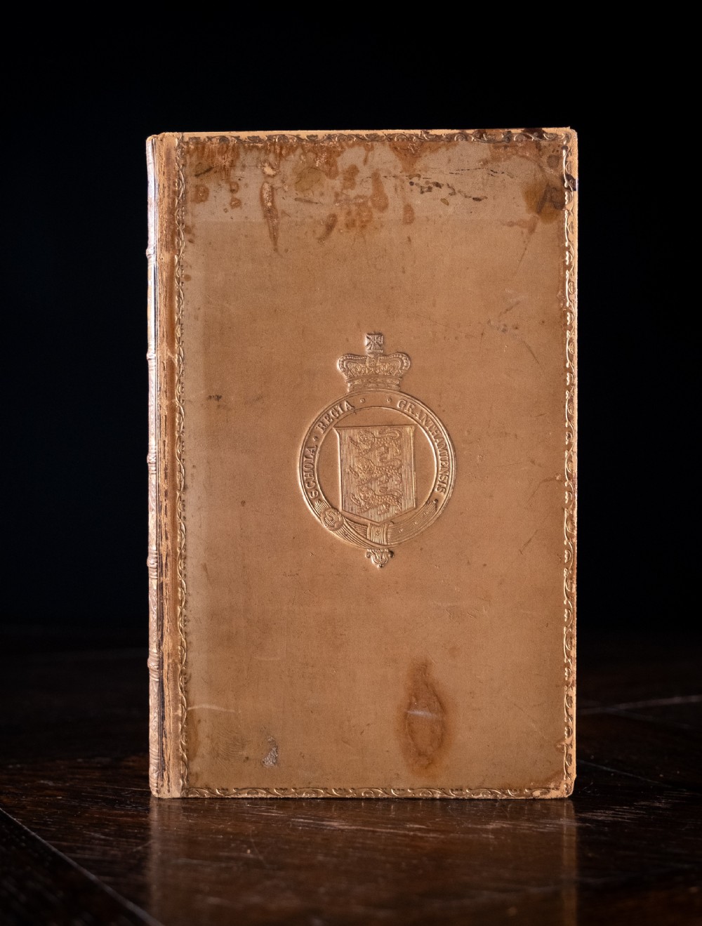 A nineteenth-century tan leather-bound book featuring ornate gilt tooling on the spine and an embossed coat of arms on the front cover. View II