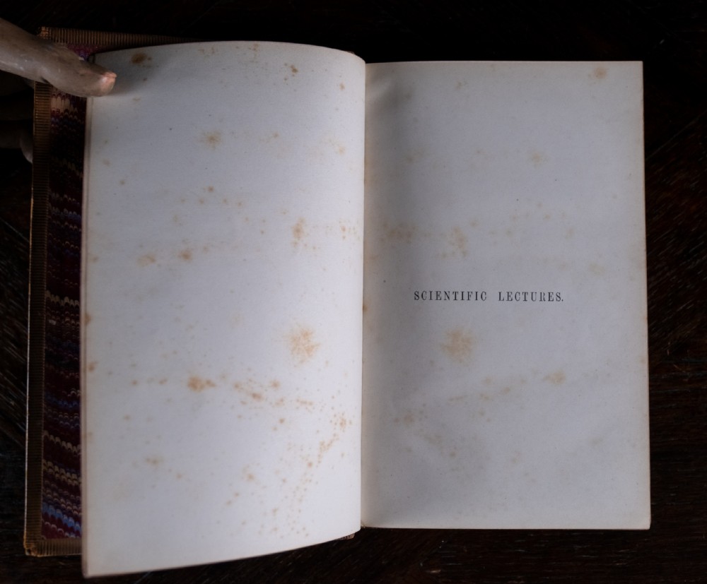 A nineteenth-century tan leather-bound book featuring ornate gilt tooling on the spine and an embossed coat of arms on the front cover. View V