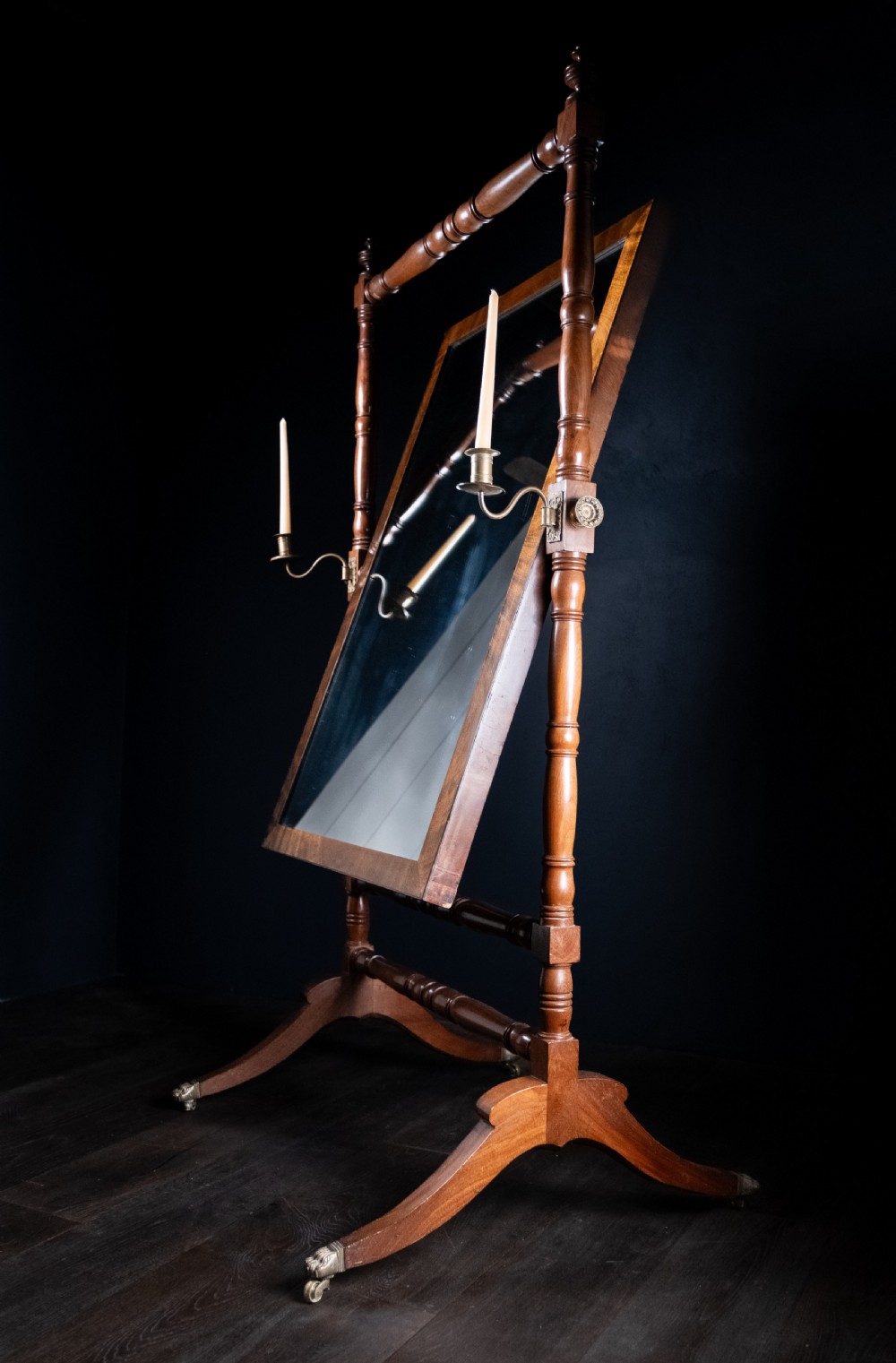 A full-length 19th-century mahogany cheval mirror featuring a rectangular swivelling glass plate within a turned wooden frame supported by splayed legs with brass castors. View VI