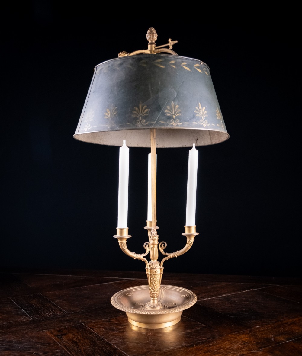 A gilt brass bouillotte lamp featuring a dark adjustable shade and three candle-style lights on a circular tray base. View VIII