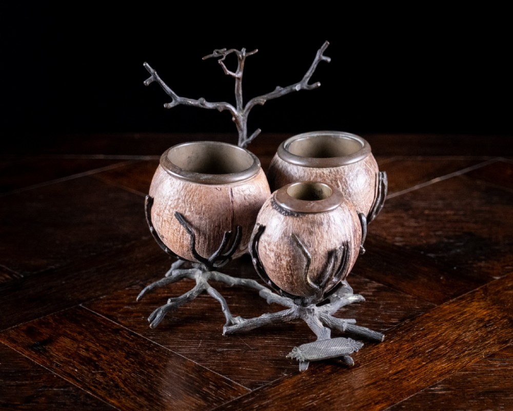 A Victorian bronze and coconut shell table vesta featuring three carved coconut vessels supported by cast metal branch mounts.