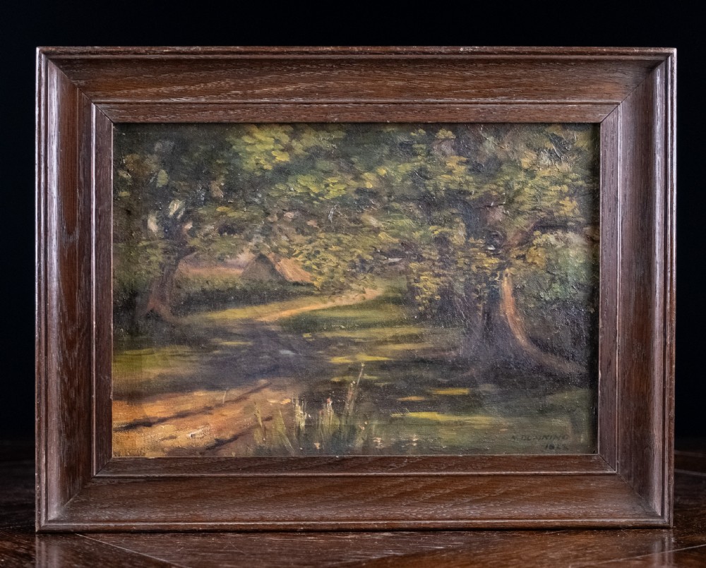 An early 20th-century oil painting on canvas depicting a shaded woodland path surrounded by dense green foliage, set within a dark molded wooden frame.