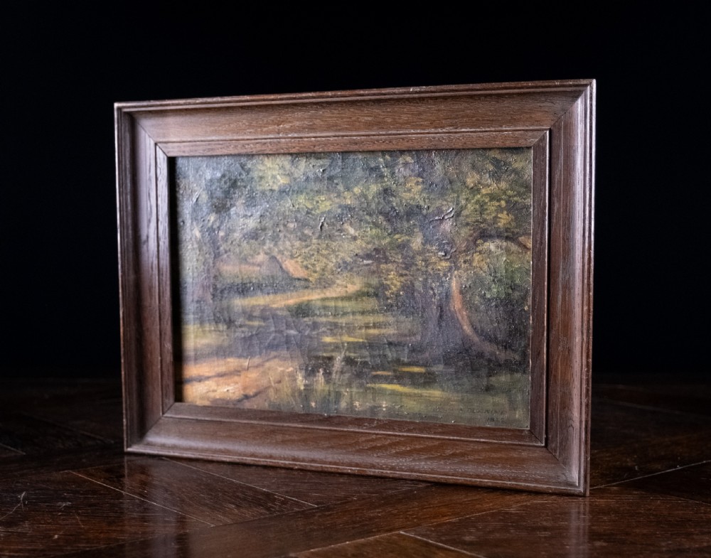 An early 20th-century oil painting on canvas depicting a shaded woodland path surrounded by dense green foliage, set within a dark molded wooden frame. View V