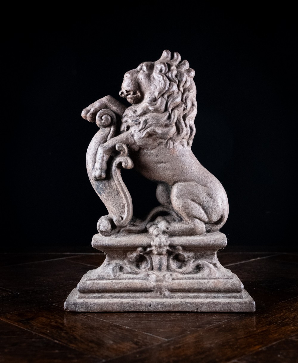 A nineteenth-century cast iron doorstop featuring a detailed rampant lion leaning against a scroll motif on a moulded plinth base. View V