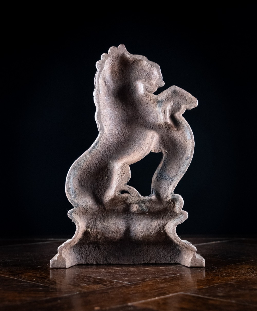 A nineteenth-century cast iron doorstop featuring a detailed rampant lion leaning against a scroll motif on a moulded plinth base. View VII