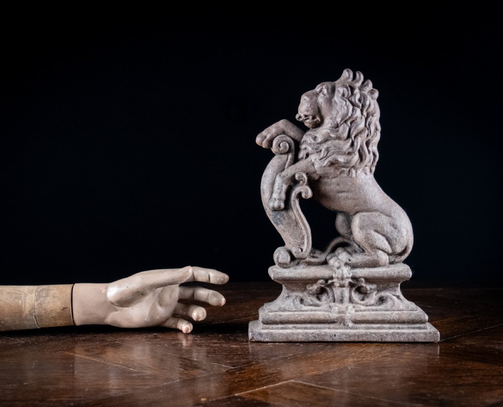 A nineteenth-century cast iron doorstop featuring a detailed rampant lion leaning against a scroll motif on a moulded plinth base. View IX