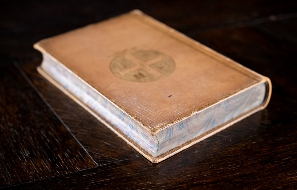 An upright 1898 tan leather-bound book featuring a gold-tooled decorative spine with floral motifs and raised bands. View IV