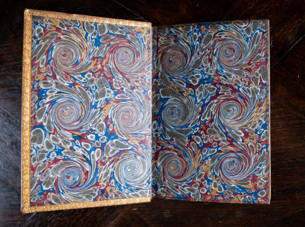 An upright 1898 tan leather-bound book featuring a gold-tooled decorative spine with floral motifs and raised bands. View VI