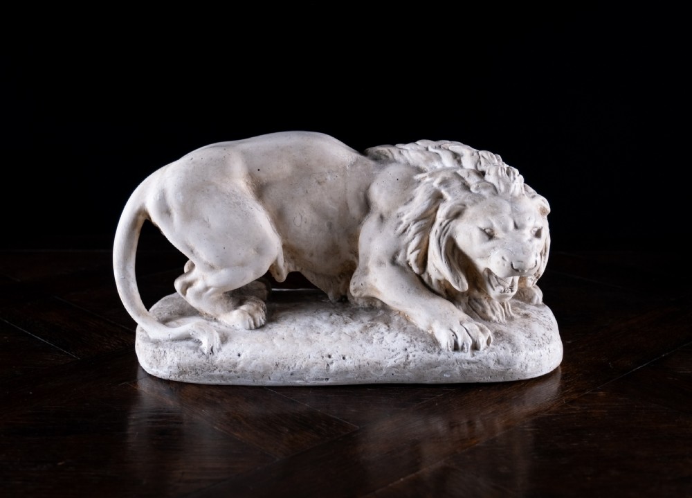 An off-white plaster sculpture depicting a prowling lion with an open mouth and detailed mane on an integral oval base. View XI