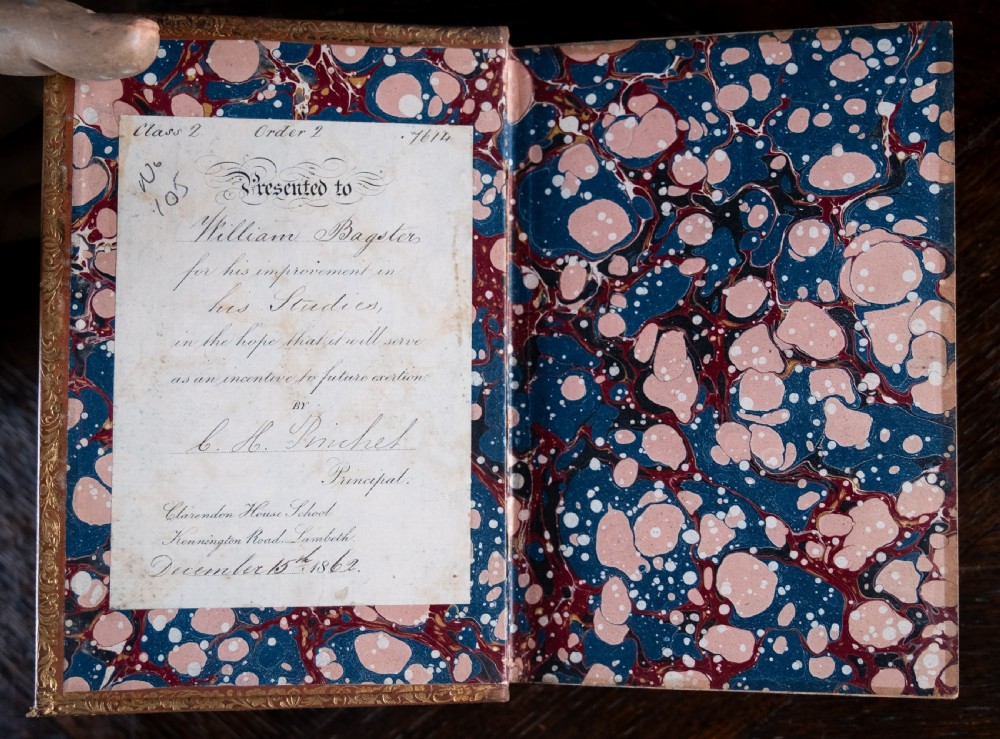 A Victorian tan leather-bound book titled Remarkable Men standing upright with ornate gold tooling on the spine and cover. View VI