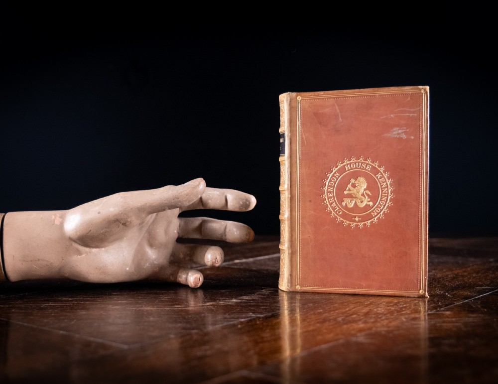 A Victorian tan leather-bound book titled Remarkable Men standing upright with ornate gold tooling on the spine and cover. View X